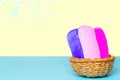 Basket with three colorful terry towels or cosmetic for body care on a blue table over yellow background with copy space. For your Royalty Free Stock Photo