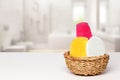 Basket with three colorful terry towels or cosmetic for body care on a white table over blurred bath background with copy space. Royalty Free Stock Photo