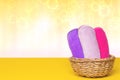 Basket with three colorful terry towels or cosmetic for body care on a yellow table over yellow background with copy space. For Royalty Free Stock Photo