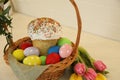 Basket with traditional Easter cake, dyed eggs and flowers on white table Royalty Free Stock Photo