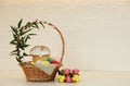 Basket with traditional Easter cake, dyed eggs and flowers on table near white brick wall. Space for text Royalty Free Stock Photo