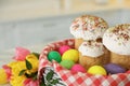 Basket with traditional Easter cakes, dyed eggs and flowers on blurred background, closeup Royalty Free Stock Photo