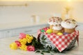 Basket with traditional Easter cakes, dyed eggs and flowers on table indoors, space for text Royalty Free Stock Photo