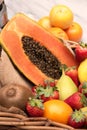 Basket of tropical fruits, oranges, pears kiwi papaya with a mixer on a wooden table. Vertical Royalty Free Stock Photo