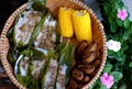 Basket of Vietnamese homemade food, boiled yellow corn, steam banana and vegan rice cake that wrap by leaf