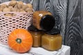 A basket of walnuts and jars of jam. Nearby there is an orange pumpkin. They stand on a white wooden box Royalty Free Stock Photo