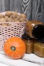 A basket of walnuts and jars of jam. Nearby there is an orange pumpkin. They stand on a white wooden box Royalty Free Stock Photo