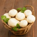 Basket of white mushrooms over wooden table