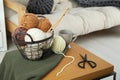 Basket with yarns, knitting needles, scissors and sweater on coffee table indoors Royalty Free Stock Photo