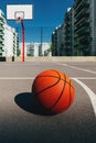 Basketball ball on outdoor court with concrete surface and backboard with hoops in background in residential district Royalty Free Stock Photo