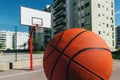 Basketball ball on outdoor court with concrete surface and backboard with hoops in background in residential district Royalty Free Stock Photo