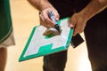 Basketball coach holds a clipboard and with a marker explain the tactic of the game to a player. Royalty Free Stock Photo