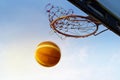 Basketball going through the basket in the blue sky background, soft and blur