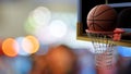 Basketball going into hoop on beautiful bokeh of colorful stadium light background. Sport and Competitive game concept.