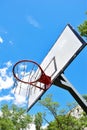 Basketball hoop and backboard against a bright blue sky with white clouds. Shot from below Royalty Free Stock Photo