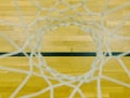 Basketball hoop in the sports hall. Look down through white string net, hardwood board