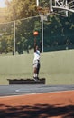 Basketball, jump and athlete scoring a goal during a match or training on an outdoor court. Fitness, sports and man