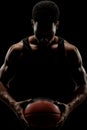 Basketball player holding a ball against black background. Serious concentrated african american man Royalty Free Stock Photo