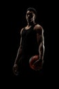 Basketball player holding a ball against black background. Serious concentrated african american man Royalty Free Stock Photo