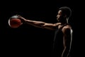 Basketball player holding a ball against black background. Serious concentrated african american man Royalty Free Stock Photo