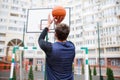 A basketball player at an outdoor stadium trains, throwing a ball into the ring, lifting his hands up. Royalty Free Stock Photo