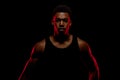 Basketball player with red side light against black background. Serious concentrated african american man