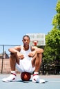 Basketball player sitting on ball Royalty Free Stock Photo