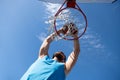 Basketball player. Sports and basketball. A young man jumps and throws a ball into the basket. Blue sky and court in the Royalty Free Stock Photo