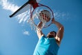 Basketball player. Sports and basketball. A young man jumps and throws a ball into the basket. Blue sky and court in the Royalty Free Stock Photo