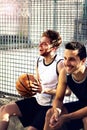 Basketball players take a break sitting on a low wall Royalty Free Stock Photo