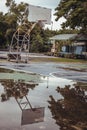 Basketball wooden backboard with the hoop metal ring and the white net show the reflection of them on the rainwater all over the