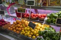 Baskets filled with orange, lemons, green bell peppers, tomatoes, and apples with colorful signs at the Municipal Market