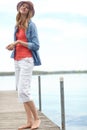 Basking in natures beauty. A happy young woman standing on a pier next to a lake. Royalty Free Stock Photo