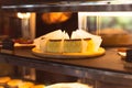 Basque burnt cheesecake in freezer in cafe with waitress in background. Royalty Free Stock Photo