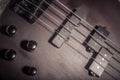 Bass electric guitar with four strings closeup. Detail of popular rock musical instrument. Close view of elements of wooden