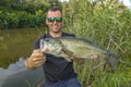 Bass fishing. Big bass fish in hands of pleased fisherman. Largemouth perch at pond Royalty Free Stock Photo