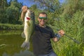 Bass fishing. Big bass fish in hands of pleased fisherman. Largemouth perch at pond Royalty Free Stock Photo