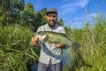 Bass fishing. Big bass fish in hands of pleased fisherman. Largemouth perch at pond Royalty Free Stock Photo