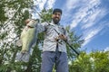 Bass fishing. Big bass fish in hands of pleased fisherman with spinning rod. Largemouth perch at pond. View from bottom Royalty Free Stock Photo