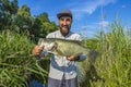 Bass fishing. Happy fisherman with big bass fish. Largemouth perch at pond Royalty Free Stock Photo