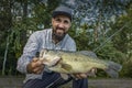 Bass fishing. Happy fisherman with big bass fish. Largemouth perch at pond Royalty Free Stock Photo