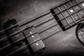 Bass guitar with four strings in black and white closeup. Detail of popular rock musical instrument. Vintage style photo of bass Royalty Free Stock Photo