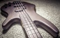 Bass guitar with four strings closeup. Detail of popular rock musical instrument. Close view of brown electric bass on carpet, Royalty Free Stock Photo