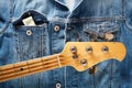 Bass guitar headstock and one dollar bills in the pocket of  denim jeans jacket Royalty Free Stock Photo