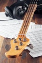 Bass guitar neck, studio headphones and music sheets on wooden table Royalty Free Stock Photo