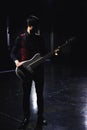 Bass guitar player in black clothes and red gillette in dark hall gothic red and black aesthetic theme concept