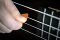 Bass guitar player with pick in his hand closeup, lesson and practice theme. Playing on bass electric guitar, live music and skill Royalty Free Stock Photo