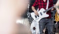 Bass guitarist in a rock or heavy metal band in a red and black plaid flannel shirt playing bass guitar on stage at a festival