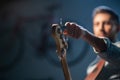 The bassist adjusts the electric bass guitar, in the foreground of the pegs and fretboard, close-up. Royalty Free Stock Photo