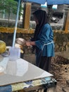 Batam, Indonesia, July 18, 2023: A young coconut seller by the roadside, peeling green coconuts to serve customers.